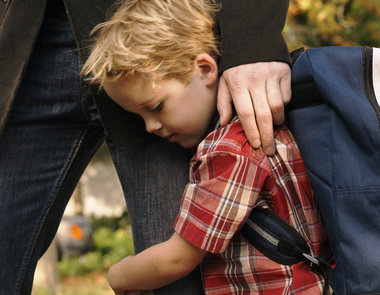 Son clinging to father's leg