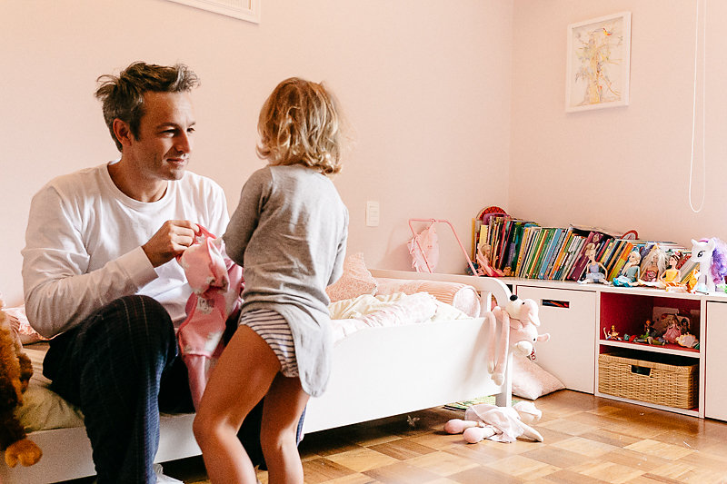 Pai vestindo sua filha - Imagem de Mika Amanto, do projeto "A day in the life of...", que mostra cotidianos de famílias pelo mundo.