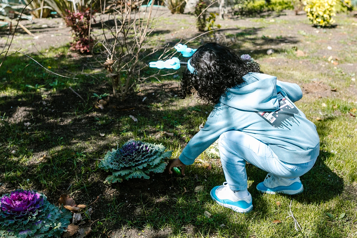 Menina pequena brincando de caça aos ovos na Páscoa - Just Real Moms