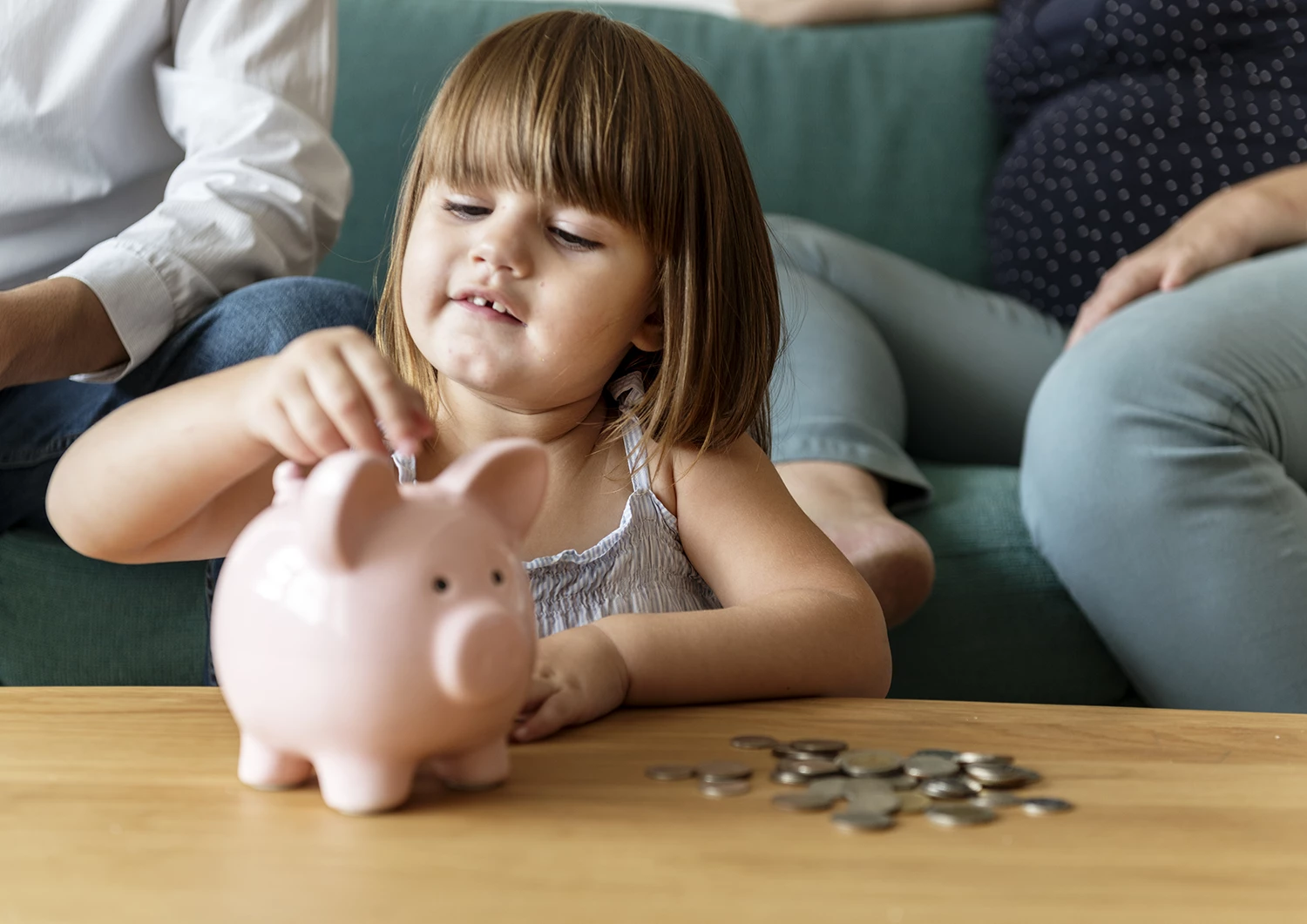 Menina com Piggy Bank e moedas com os pais - Just Real Moms