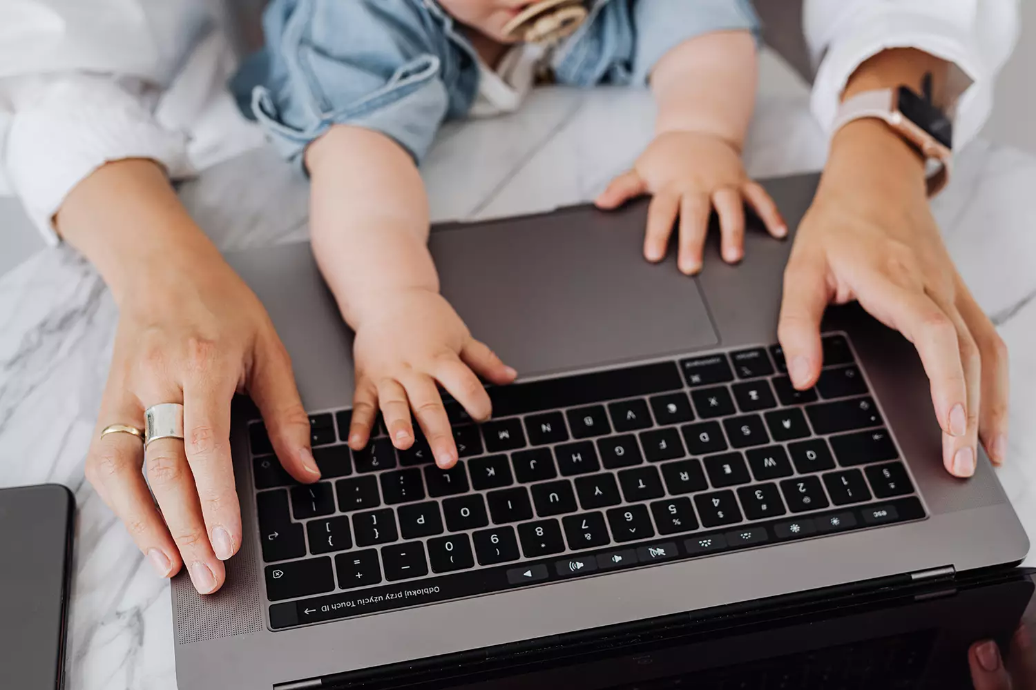Mãos de mãe e bebê em cima de um notebook aberto - Just Real Moms