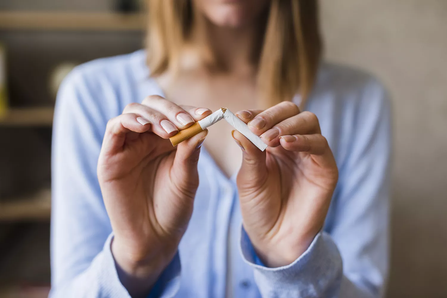 Close nas mãos de mulher loira quebrando um cigarro