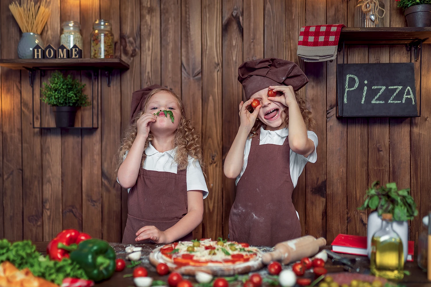 Duas meninas pequenas vestidas de chef fazendo pizza Duas meninas pequenas vestidas de chef fazendo pizza