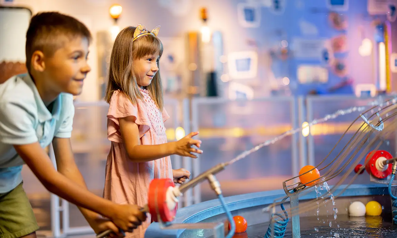 Menina e menino brincando em um museu de ciências