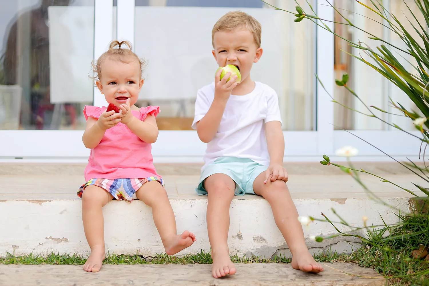 casal de irmão sentados na varanda comendo frutas casal de irmão sentados na varanda comendo frutas