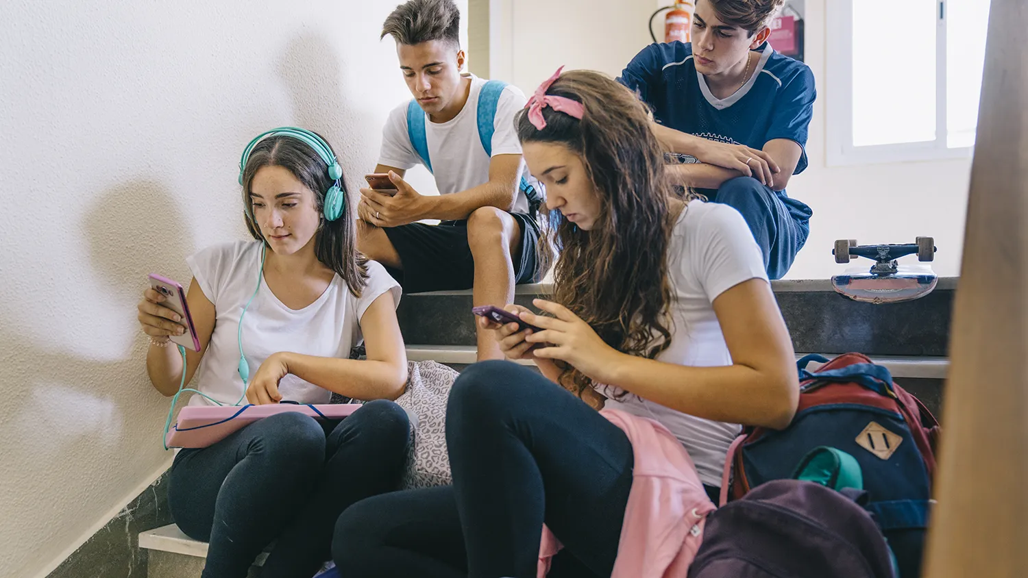 Adolescentes usando celular na escadaria da escola