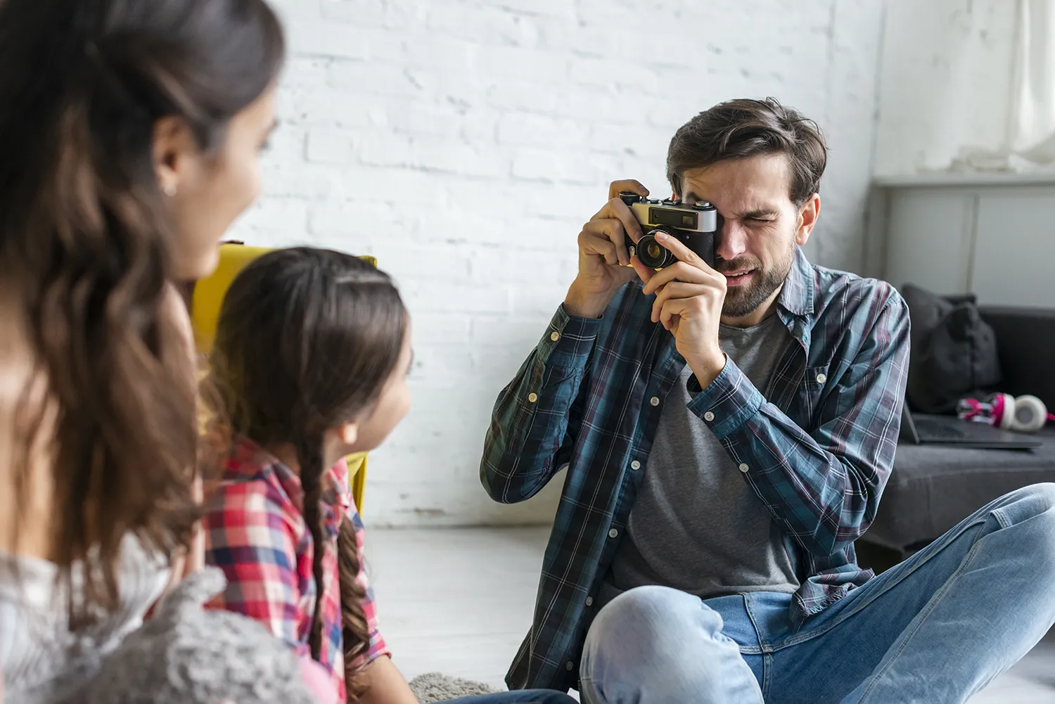 Pai tirando foto da esposa e sua filha em casa