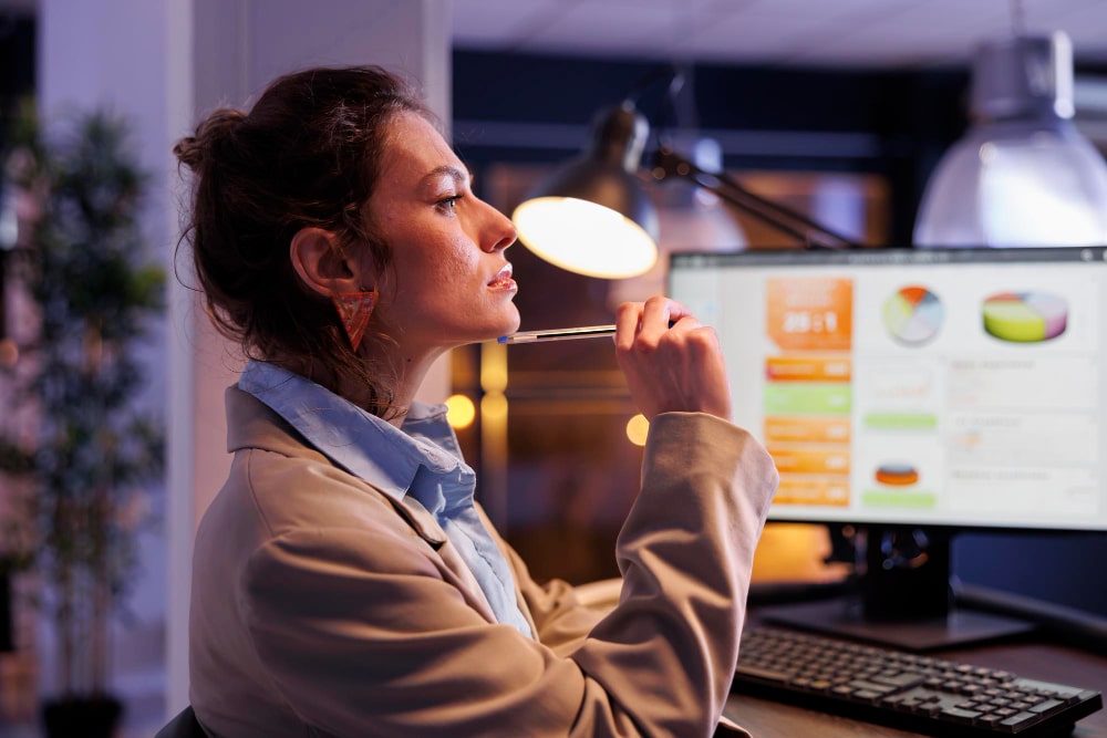 Mulher analisando gráficos e indicadores de inovação em um ambiente de trabalho moderno, avaliando o desempenho de iniciativas disruptivas.