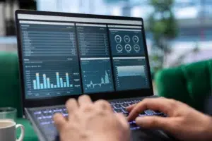 Pessoa utilizando notebook com dashboards inteligentes na tela para análise de dados.